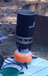 A Jetboil camping stove and pot mounted on a gas canister outdoors.
