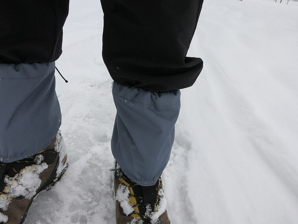 Short gaiters fitted over hiking boots in snow.