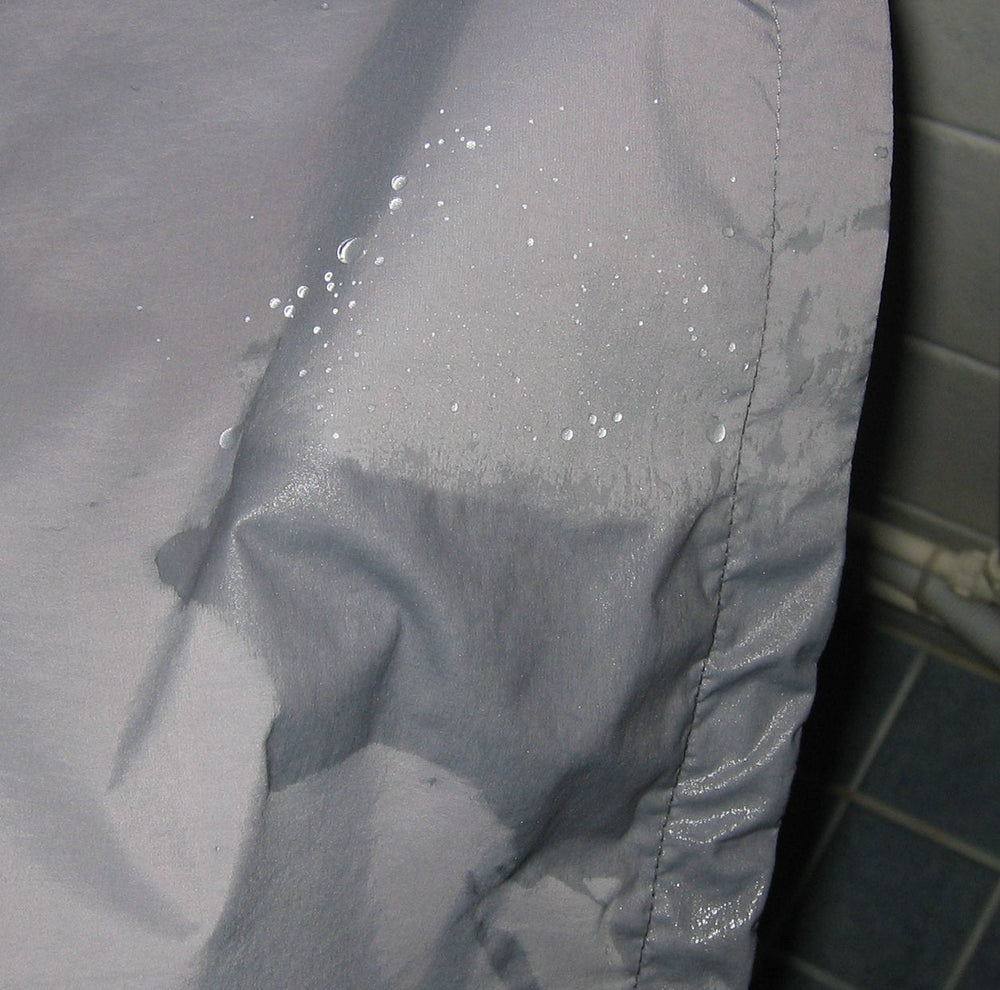Water droplets beading on the outer fabric of a shell jacket.