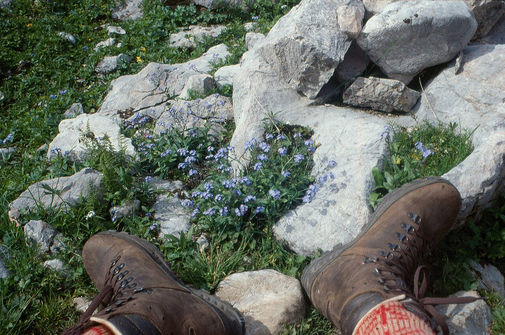 Brown leather hiking boots on a walker’s feet, showing the laces and upper fittings.