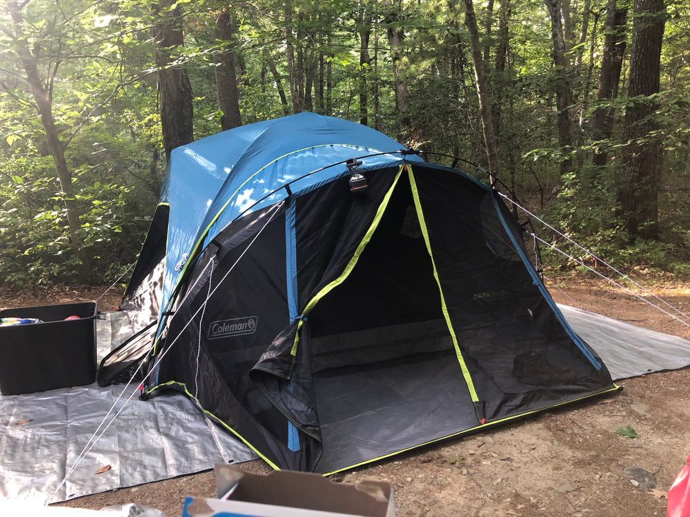 A camping tent pitched among trees.