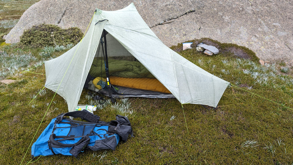 A sleeping bag inside a pitched tent, with a pack beside it.