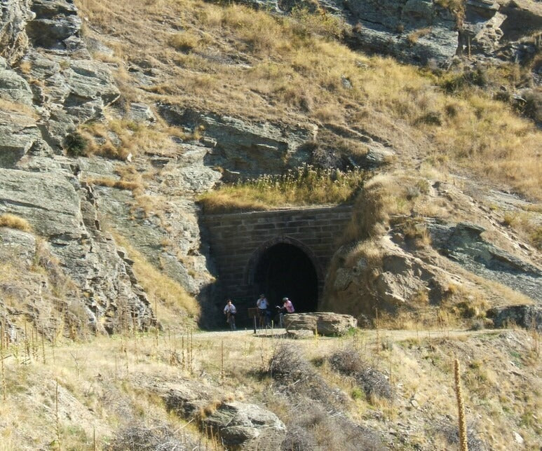 Cyclists beside a tunnel on the Otago Central Rail Trail
