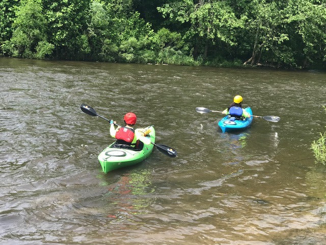 Kayakers wearing lifejackets while paddling on the Cuyahoga River