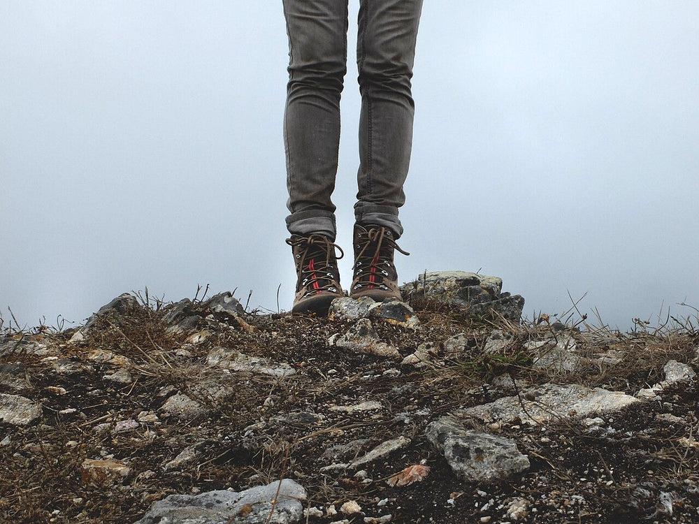Hiker's trouser legs and boots resting on rock