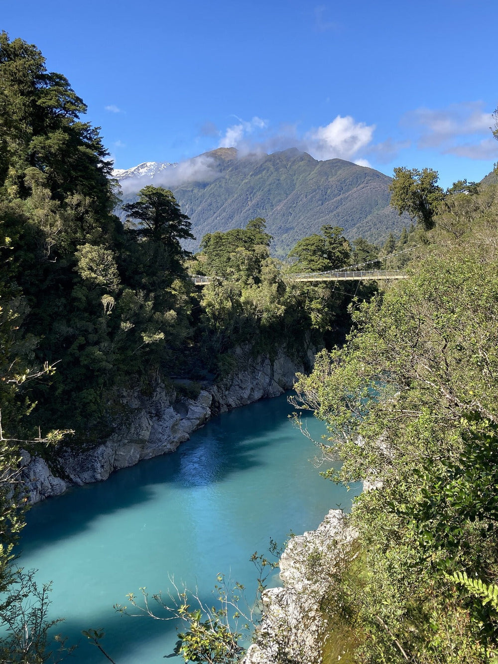 Turquoise river, forest and suspension bridge at Hokitika Gorge.