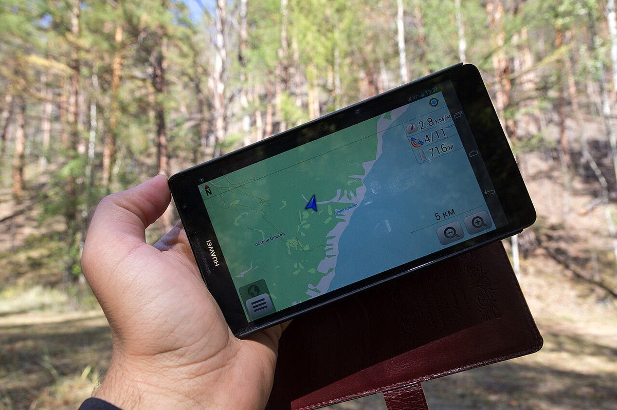 Person holding a smartphone map outdoors near Lake Baikal