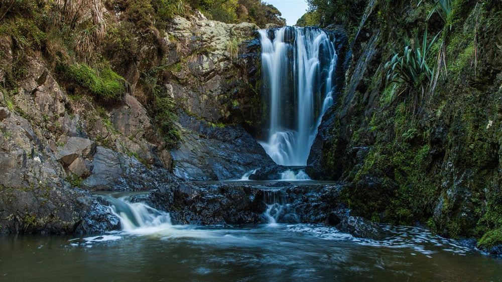 Piroa Falls dropping into a rocky pool in Waipū Gorge.