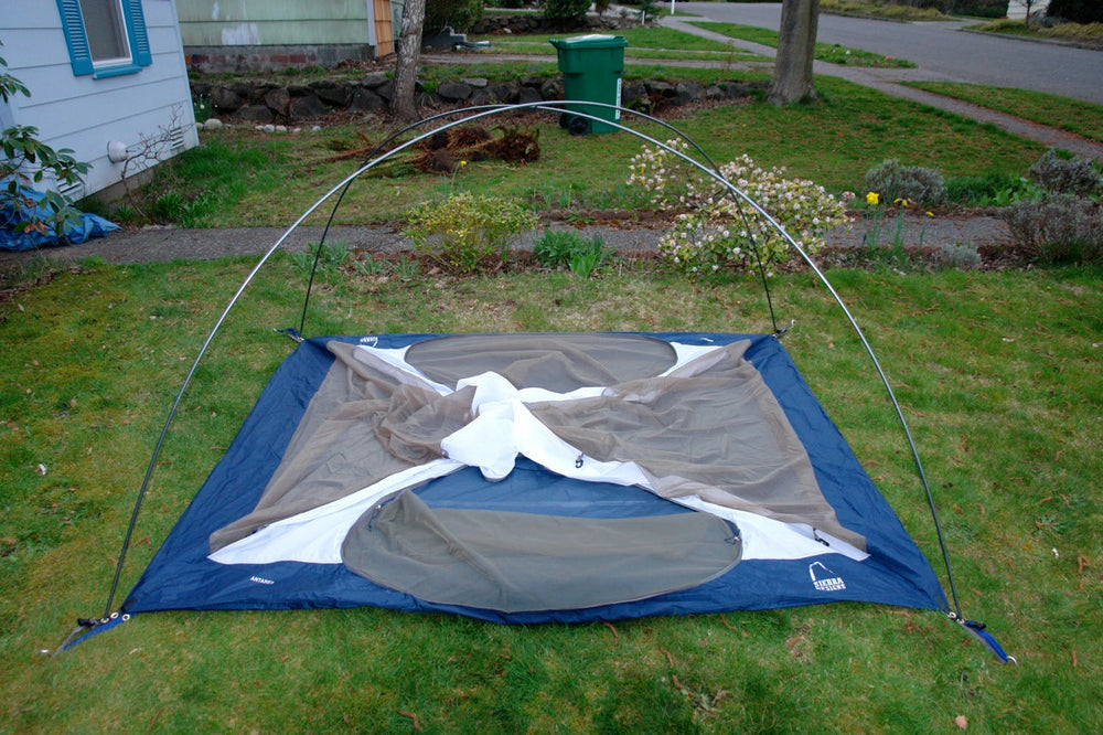 A pitched tent frame with crossing poles visible before the outer fly is fitted.