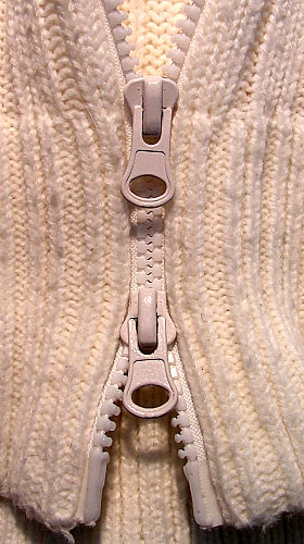 A two-way clothing zip with two sliders and fabric tape.