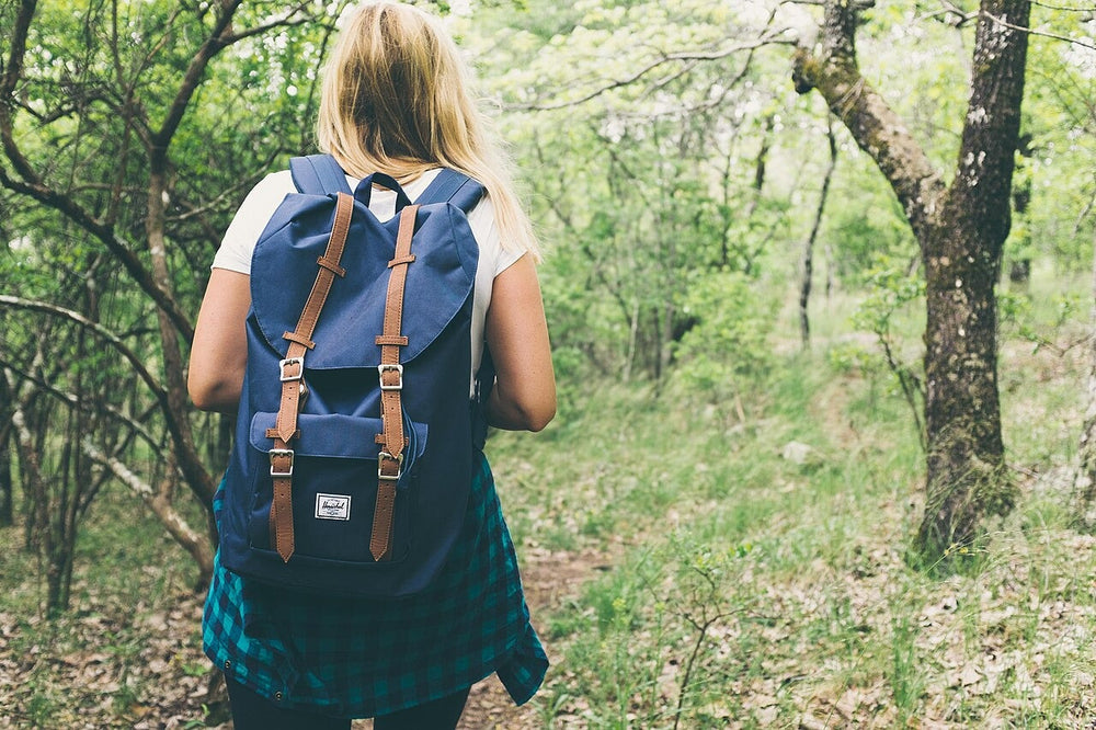 Solo walker carrying a backpack through green forest