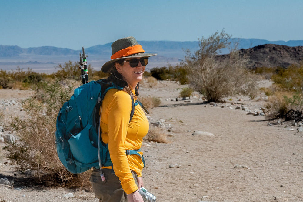 Hiker wearing a brimmed hat and covering clothing in a dry landscape