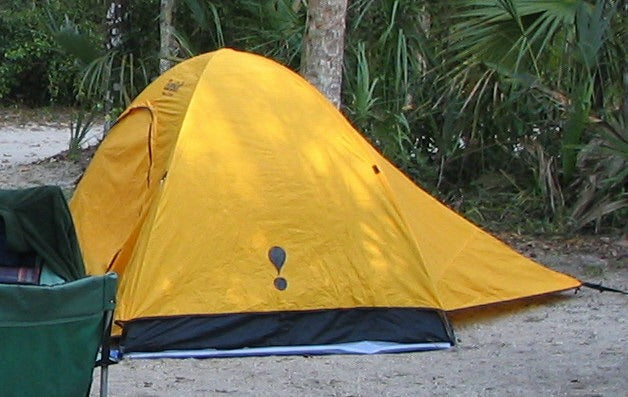Yellow backpacking tent pitched in a forest clearing