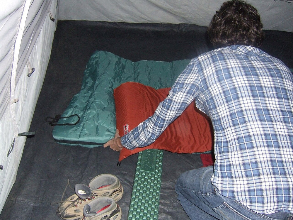 Person adjusting a sleeping bag inside a tent