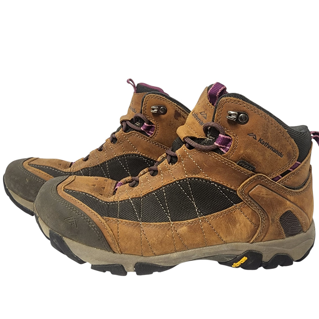 Pair of brown hiking boots with purple laces on a white background